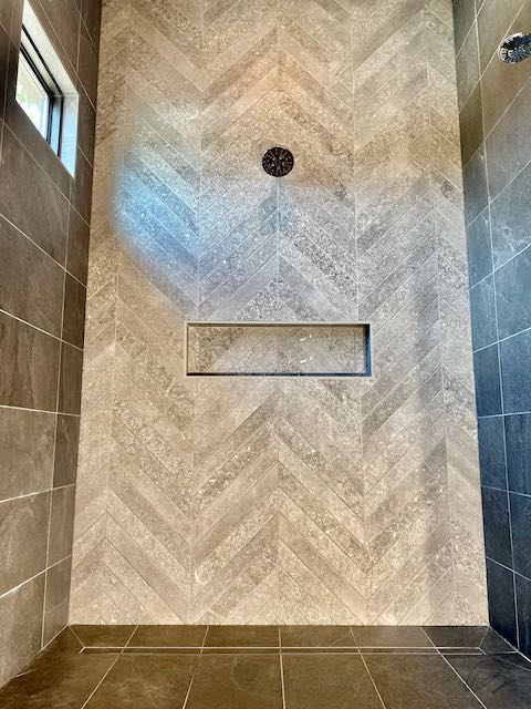 Grey tile shower with directional tile wall design and shelf installed by Floored by Barrett in the Temple Belton area