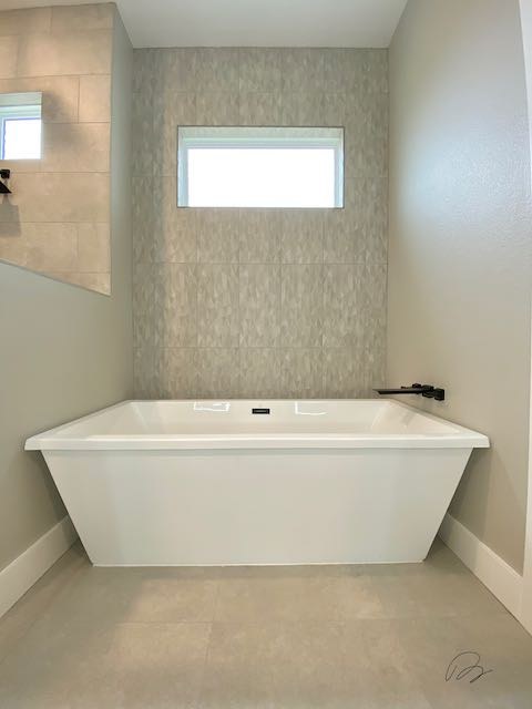 Grey tile wall and floor with rectangular bathtub installed by Floored by Barrett in the Temple Belton area