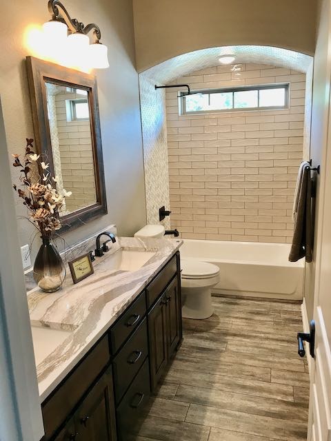 White tile shower / bathtub and grey hardwood bathroom floor installed by Floored by Barrett in the Temple Belton area